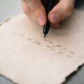 close up shot of a person writing on a paper journal writing