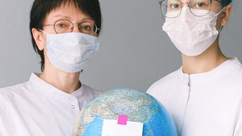people with face masks and latex gloves holding a globe