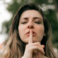 woman signaling for silence outdoors in fall