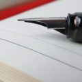 selective focus photography of calligraphy pen placed on top of open notebook journal jounal