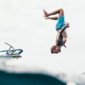 man wearing blue shorts about to dive on body of water